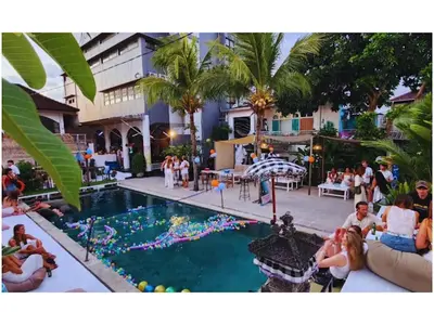 a group of people sitting around a pool at a resort at Mycapsule Bali in Seminyak