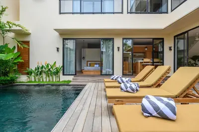 a pool with lounge chairs and a house at Spacious 4BR Family Pool Villa in Sanur