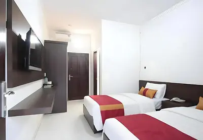 a hotel room with two beds and a television at Wisp Sunset in Legian