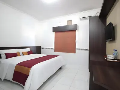a bedroom with a large bed and a tv at Wisp Sunset in Legian