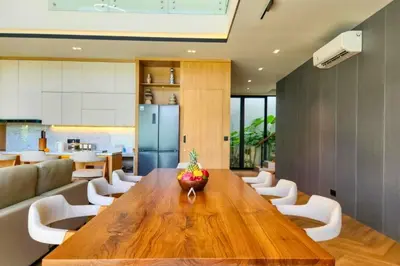 a dining room with a wooden table and white chairs at Foujina Elegant 4 BR Private Pool Villa in Jimbaran