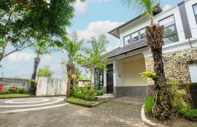 a house with palm trees in front of it at D'Maya Villa Jimbaran By Island Escape in Jimbaran