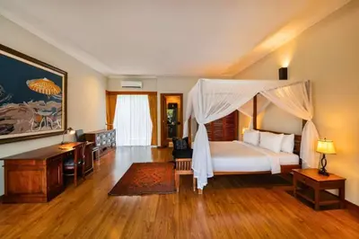 a bedroom with a canopy bed and a desk at Ghania Peaceful 3 BR Private Pool Villa in Jimbaran