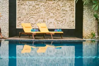 two yellow chairs sitting next to a swimming pool at Ghania Peaceful 3 BR Private Pool Villa in Jimbaran