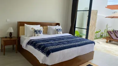 a bedroom with a large bed with blue and white sheets at Narayuka private villa in Seminyak