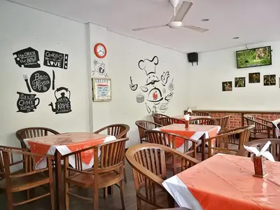 a dining room with tables and chairs and signs on the wall at Dlima Hotel Villa in Legian