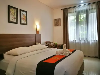 a bedroom with a large bed and a window at Dlima Hotel Villa in Legian