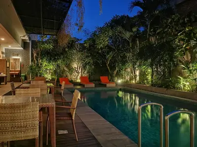 a swimming pool with tables and chairs next to a resort at Dlima Hotel Villa in Legian