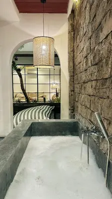 a bath tub in a room with a stone wall at The Wina Villa Canggu by The Wina Resorts in Canggu