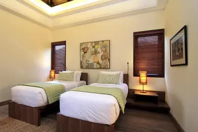 two beds in a room with windows and a ceiling at Villa Suar Drupadi in Seminyak