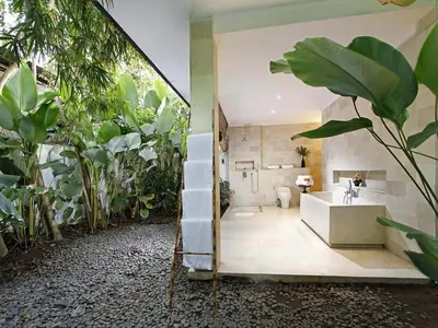 a bathroom with a tub and a shower with plants at Villa Mona in Canggu