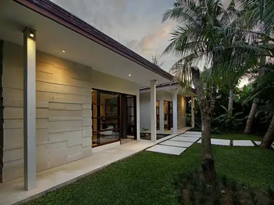 a house with a palm tree in front of it at Villa Mona in Canggu