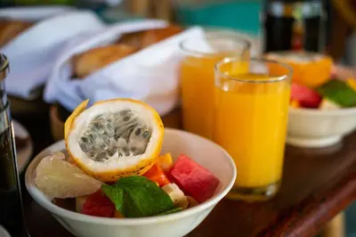 a bowl of fruit on a table with two glasses of orange juice at Poppies Bali in Kuta