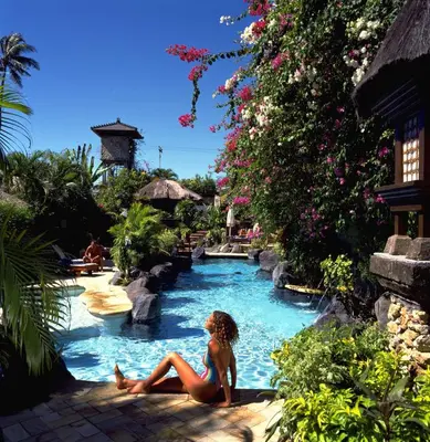 a woman sitting in a pool at a resort at Poppies Bali in Kuta