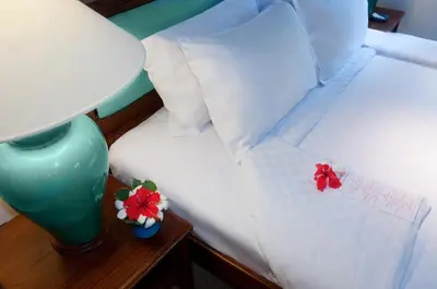 a bed with two pillows and a table with a lamp at Poppies Bali in Kuta