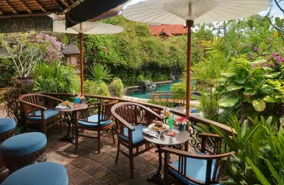 a patio with tables and chairs and a pool at Poppies Bali in Kuta