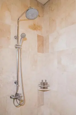 a shower with a shower head in a bathroom at Grand Kesambi Resort and Villas Seminyak in Seminyak