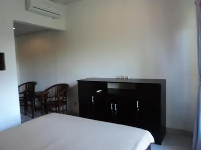 a bedroom with a bed and a table and chairs at De Dukuh Guest House in Kuta