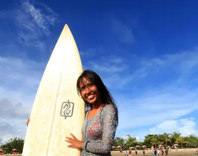 a woman is holding a surfboard on the beach at Villa Sammy in Seminyak