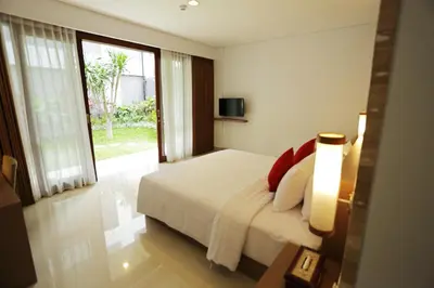 a bedroom with a bed and a large window at Grand La Walon Hotel in Legian