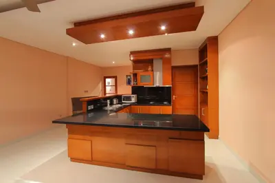 a kitchen with wooden cabinets and a black counter top at Benoa Rose Residence One in Nusa Dua