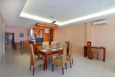 a dining room and living room with a table and chairs at Benoa Rose Residence One in Nusa Dua