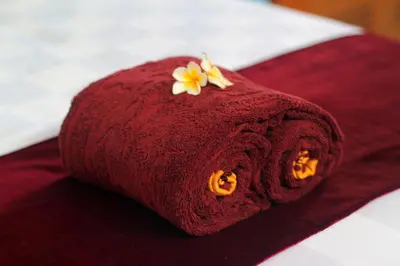 a red towel with a flower on top of a bed at Benoa Rose Residence One in Nusa Dua