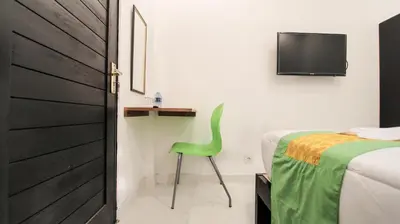 a bedroom with a green chair next to a bed at Akatara Stay in Jimbaran