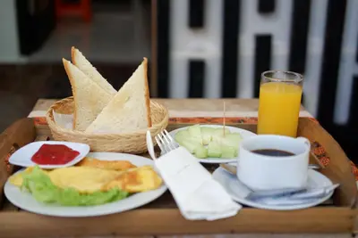 a tray with a plate of breakfast food and a glass of orange juice at Akatara Stay in Jimbaran