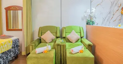 a room with two green chairs and a bed at Swiss-Belinn Seminyak in Seminyak