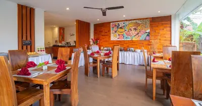 a restaurant with wooden tables and chairs with red flowers on them at Swiss-Belinn Seminyak in Seminyak