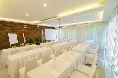 a conference room with white tables and chairs and a screen at Swiss-Belinn Seminyak in Seminyak
