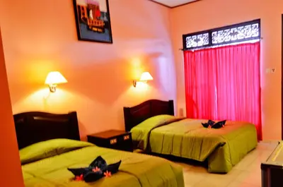 a hotel room with two beds and a red curtain at Pesona Beach Inn in Kuta