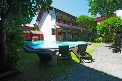 a pool table in front of a building with two chairs at Pesona Beach Inn in Kuta