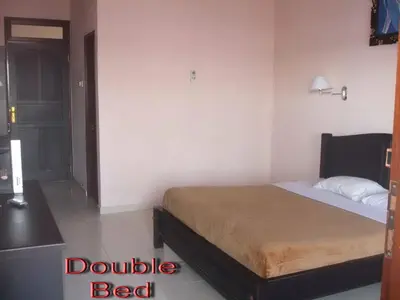 a bedroom with a bed in a room with a desk at Pesona Beach Inn in Kuta