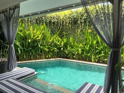 a swimming pool in front of a garden at Villa Ozamiz Seminyak in Seminyak