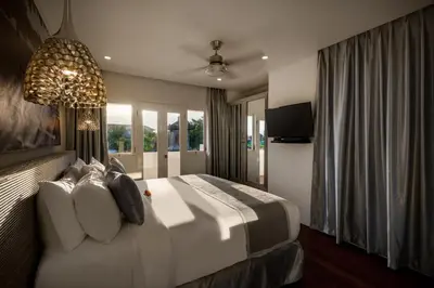 a bedroom with a large white bed and a chandelier at Villa Ozamiz Seminyak in Seminyak