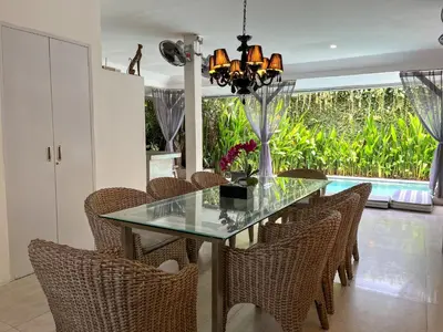 a dining room with a glass table and chairs at Villa Ozamiz Seminyak in Seminyak