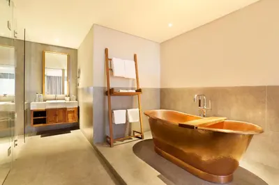 a bathroom with a copper tub and a sink at Tijili Hotel Seminyak in Seminyak