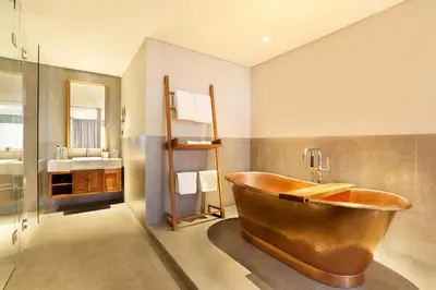 a bathroom with a copper tub and a sink at Tijili Hotel Seminyak in Seminyak