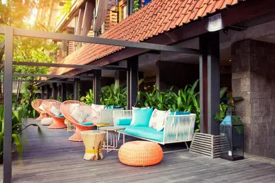 a deck with wicker chairs and chairs on a building at Tijili Hotel Seminyak in Seminyak