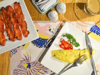 a table with two plates of food with eggs and broccoli at Tijili Hotel Seminyak in Seminyak