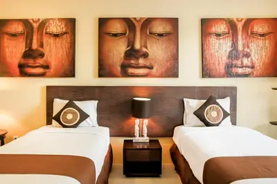 two beds in a hotel room with portraits on the wall at Samana Villas in Legian