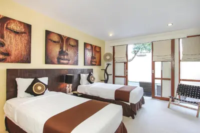 two beds in a room with paintings on the wall at Samana Villas in Legian