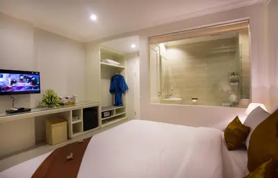 a bedroom with a large white bed and a television at Amalfi Hotel Seminyak in Seminyak