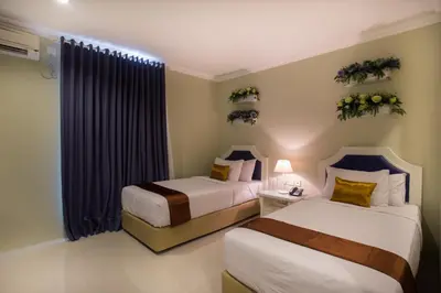 a hotel room with two beds and a window at Amalfi Hotel Seminyak in Seminyak