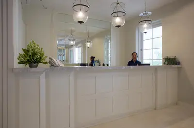 a woman standing at a counter in front of a mirror at Amalfi Hotel Seminyak in Seminyak
