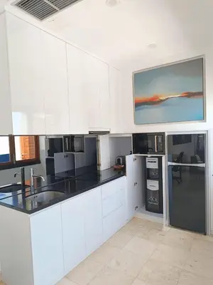 a kitchen with white cabinets and black counter tops at Kamil Villas in Seminyak