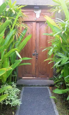 a wooden door with a pathway in front of it at Taman Amertha Villas by Maha Bali in Seminyak