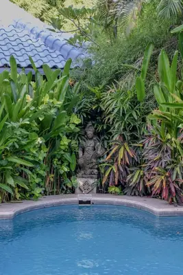 a garden with a statue next to a swimming pool at Ben Bali Villa in Seminyak
